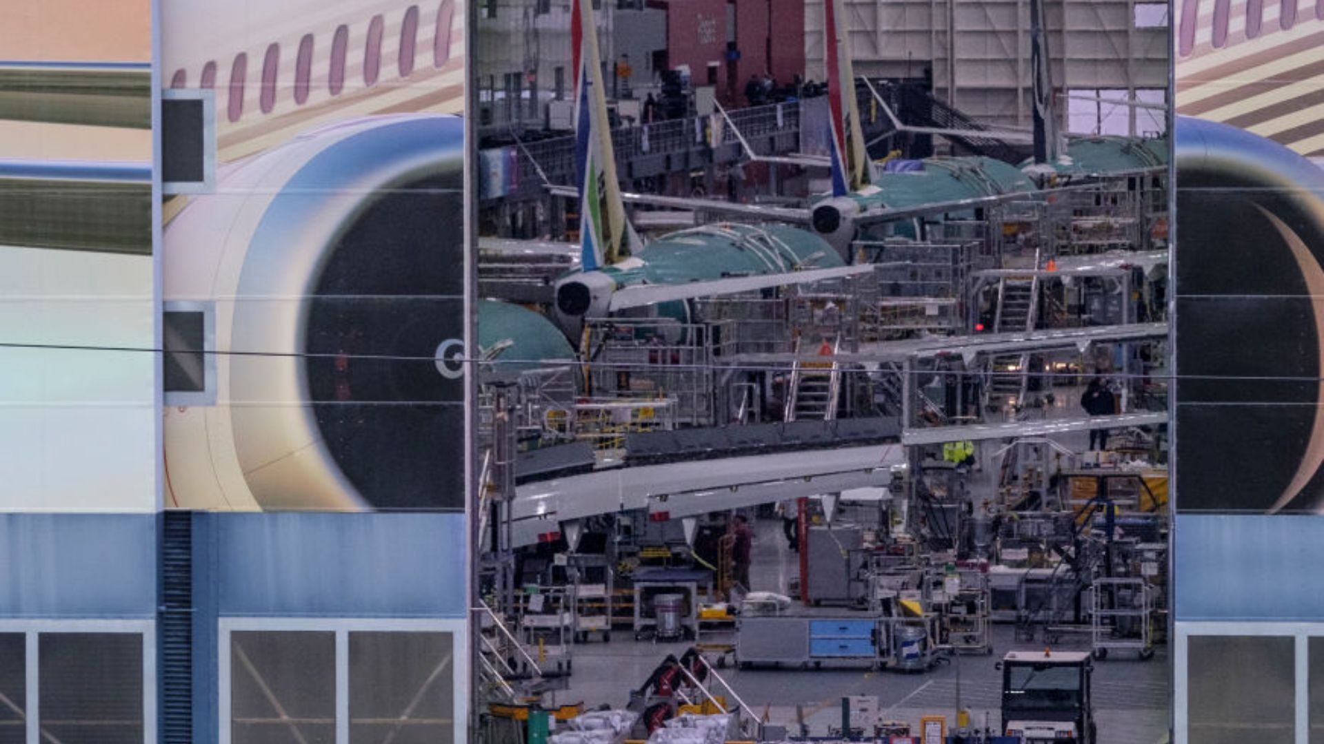 Inside view of an industrial airplane assembly area with multiple green aircraft structures in various stages of assembly