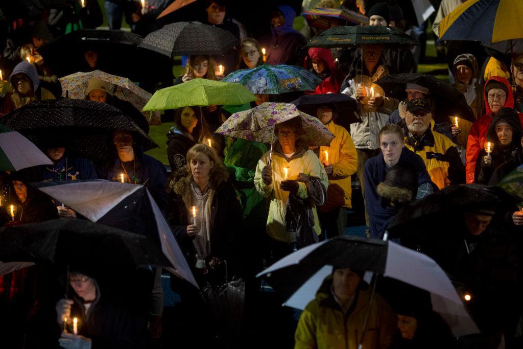 Mourners listen while names are read aloud during a community vigil at Newtown High School