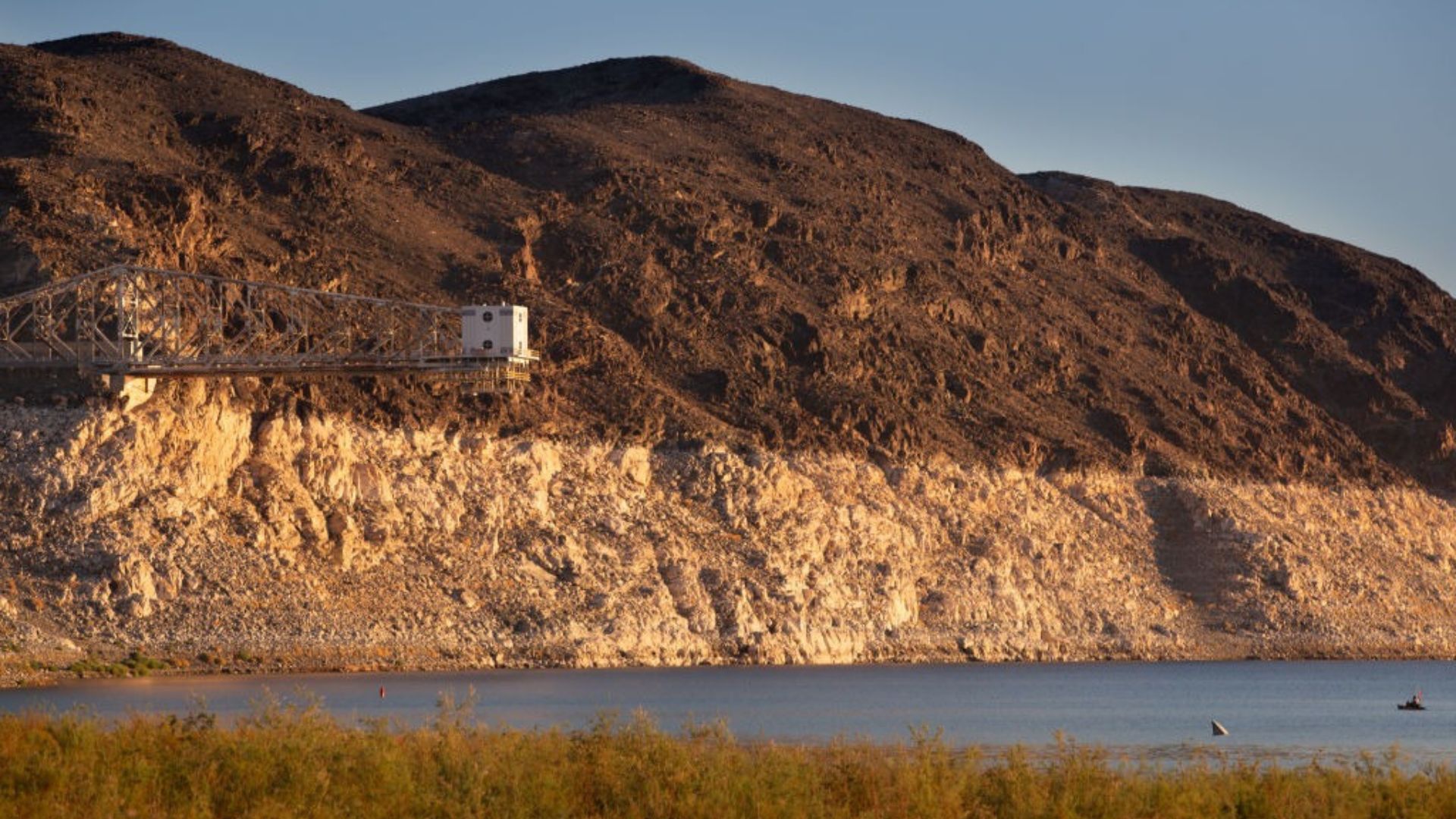 A view of Lake Powell with mountains in the background and grass in the foreground