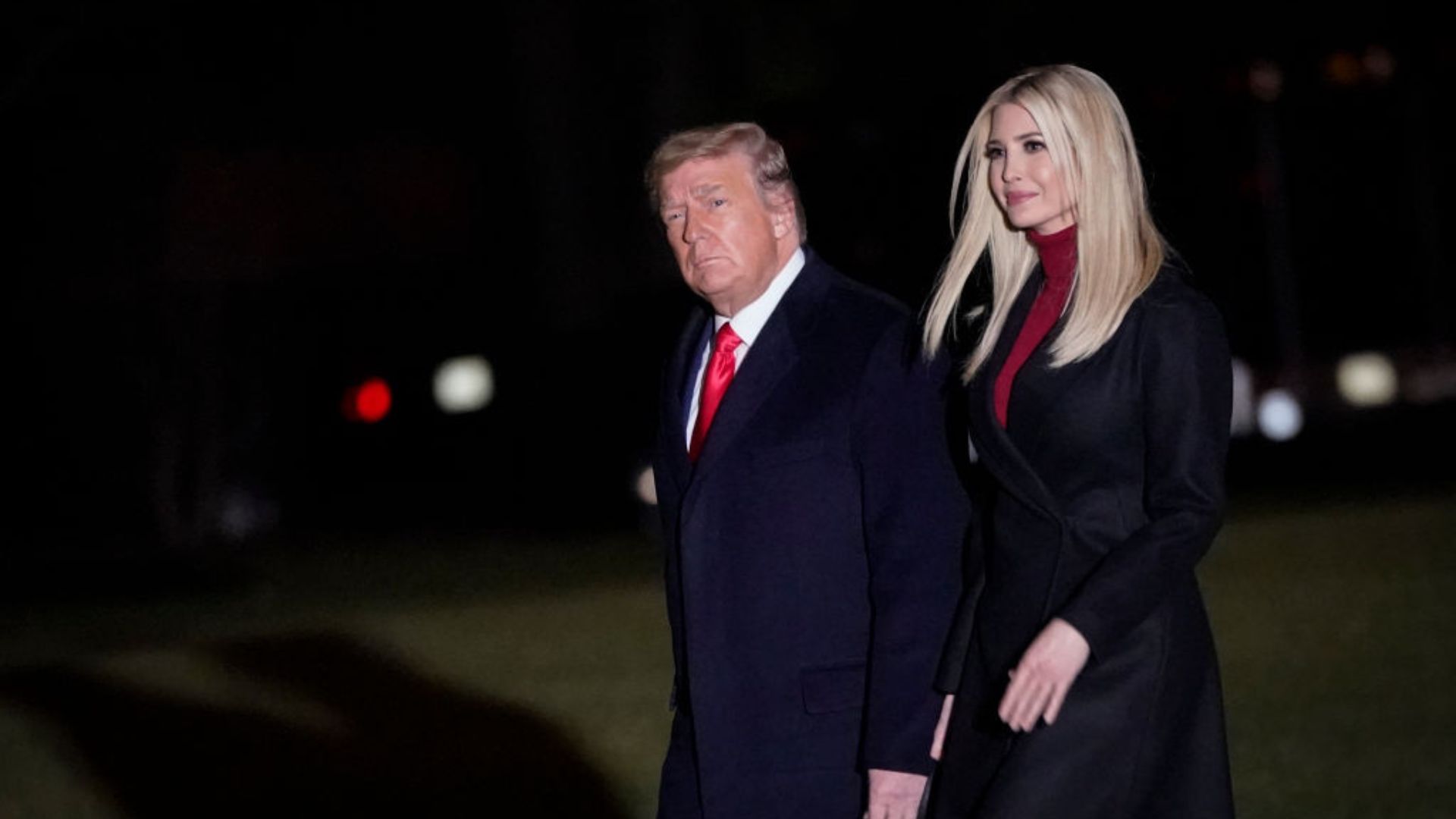 Donald Trump, wearing a navy suit and red tie, looks to his left with a serious expression. To his right, Ivanka Trump, wearing a black coat with a red turtleneck
