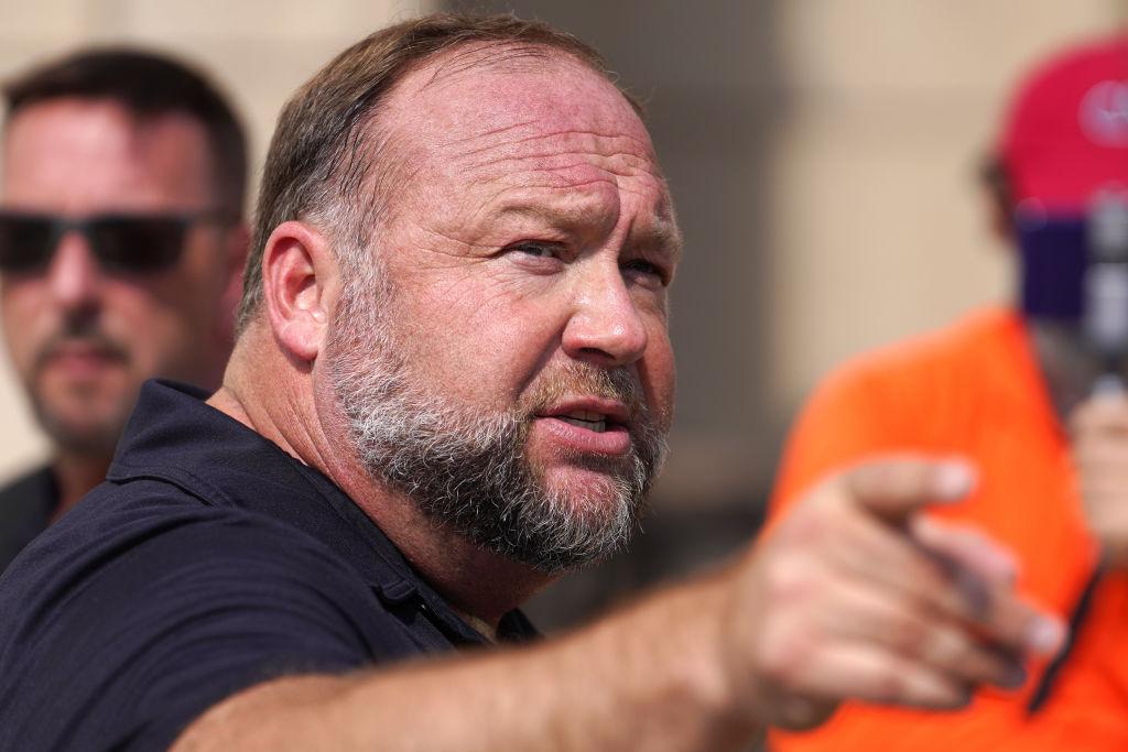 Alex Jones points past the camera and looks concerned
