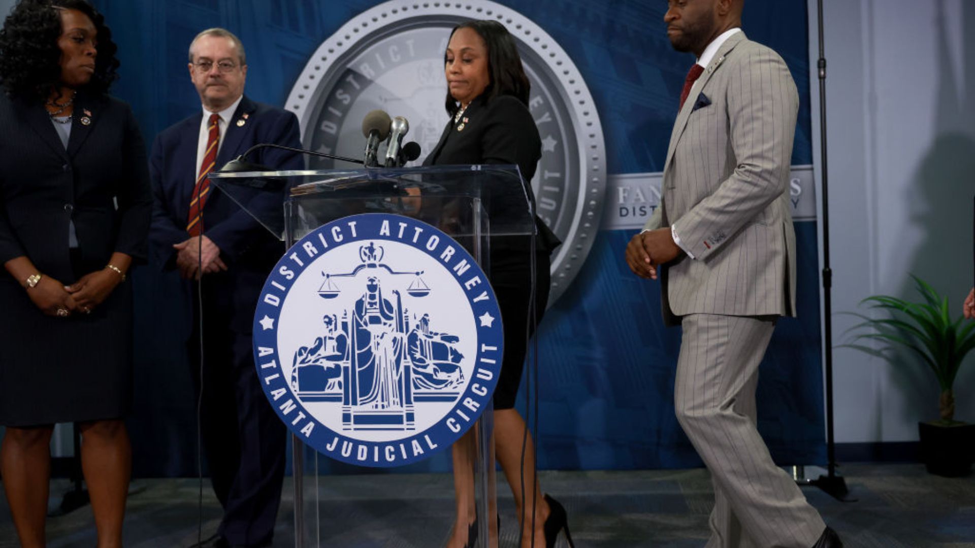 District Attorney Fani Willis speaking at a press conference, standing at a podium with the seal of the Atlanta Judicial Circuit