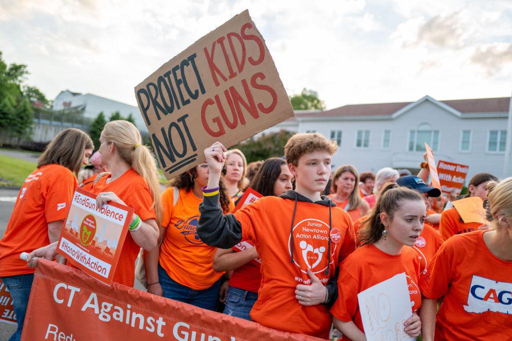 People hold up signs during a rally for National Gun Violence Awareness Day on June 03, 2022, in Newtown, Connecticut