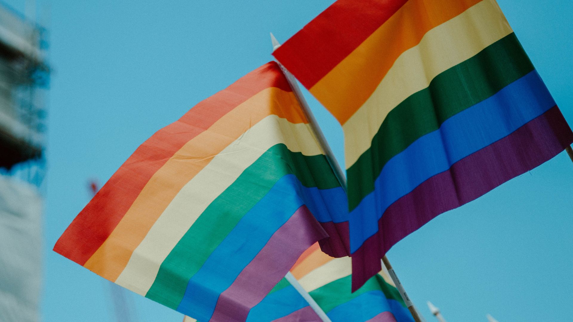 Close-up of vibrant rainbow-colored flags fluttering against a clear blue sky