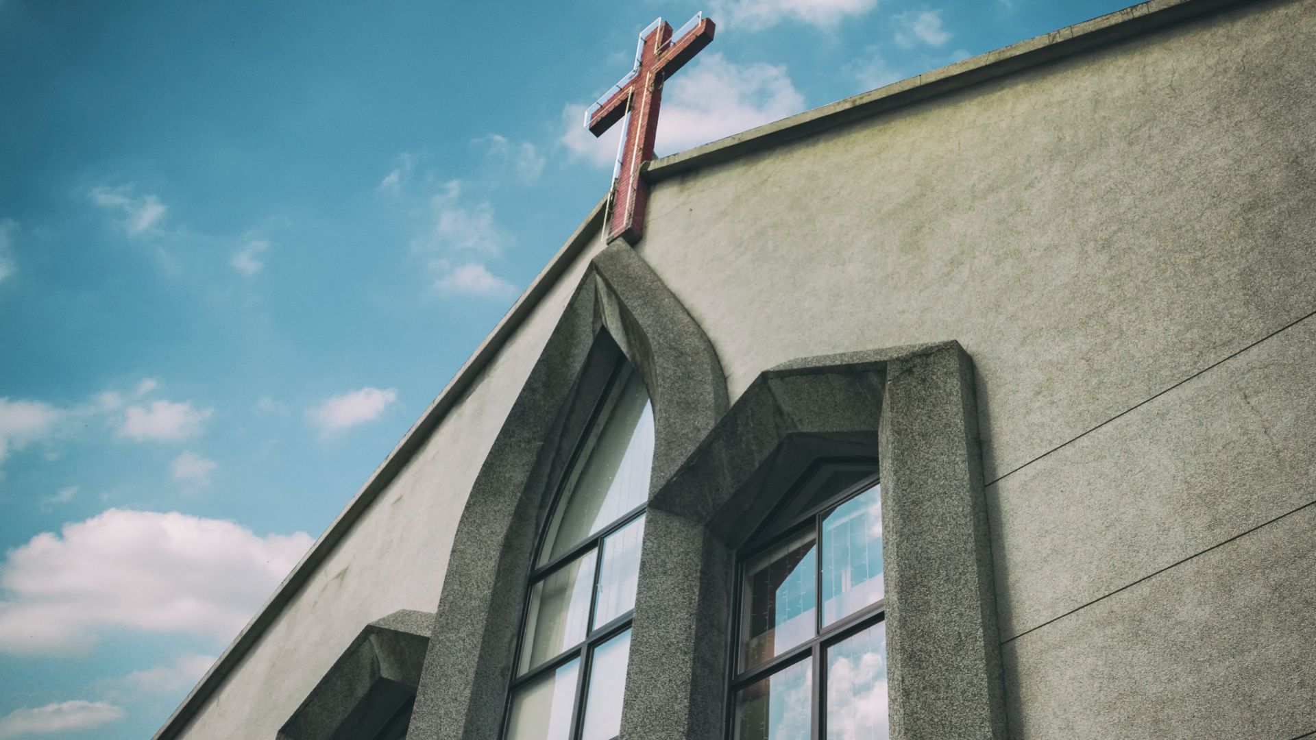 An image of the exterior of a church building under a blue sky with scattered clouds