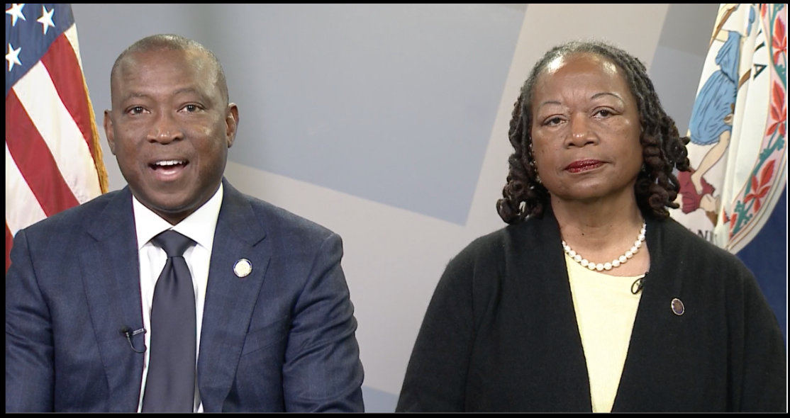 Democrat Don Scott (left) and Mamie Locke (right) between two flags.