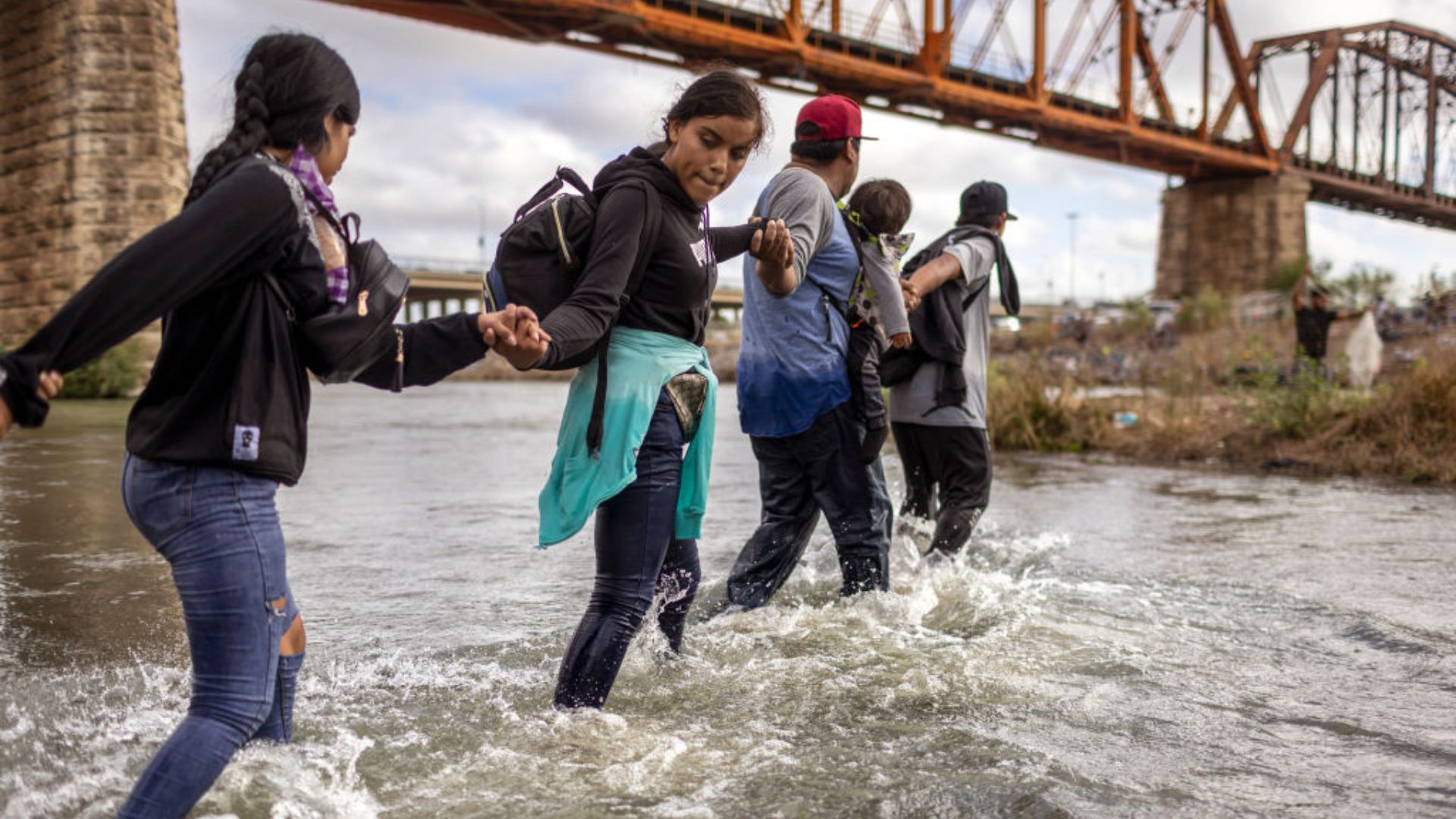A group of people wading through a river, with water up to their shins