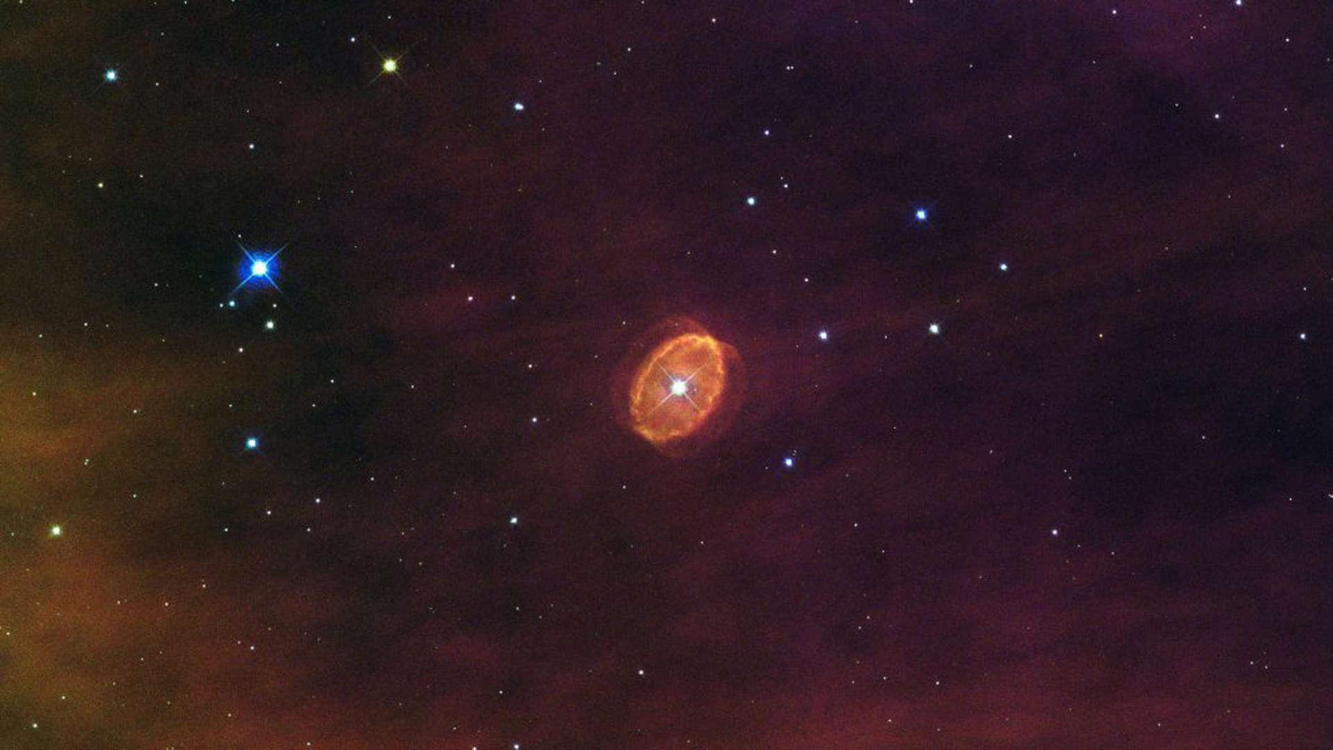 A nebula with a giant star at its center and other shiny objects around it.